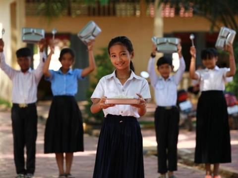 Children pose with school lunch trays for school meals