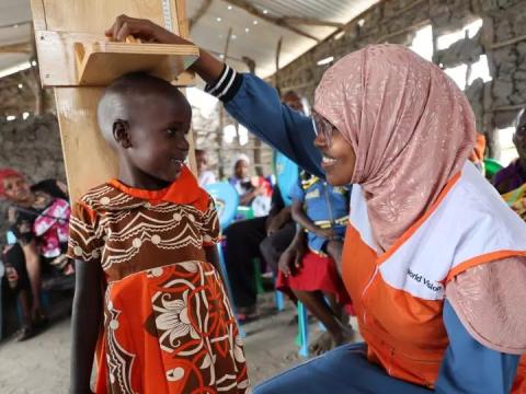 A World Vision staff member measures the height of a child.