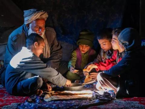 Amir, 55, and his children eating a meal in Herat, Afghanistan together.