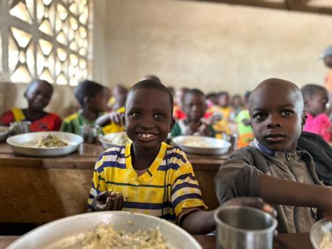 A child smiles with a school meal in Bouar at a school