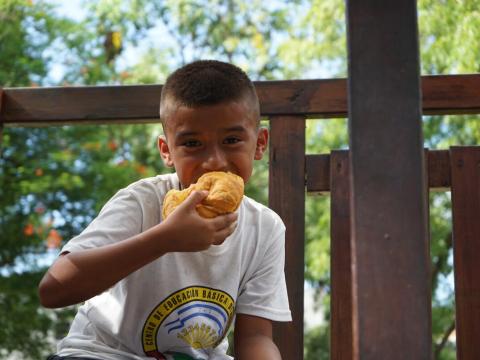 Boy eats a meal in a white shirt