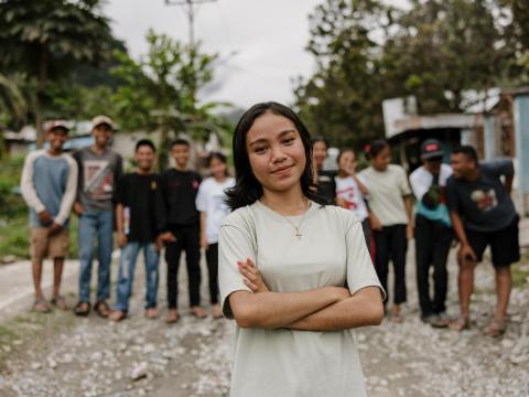 Tasya stands in front of a group of children, arms crossed