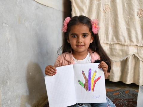 Child with drawing, smiling for camera