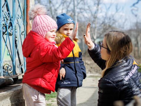 World Vision staff member gives high-fives to children