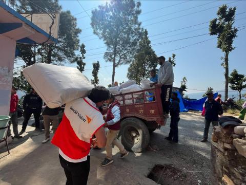 World Vision staff member carries sack of life-saving supplies