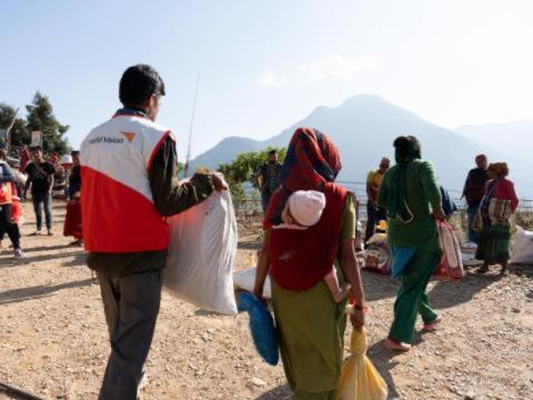 A World Vision staff member helps a woman carry a bag of basic necessities. 